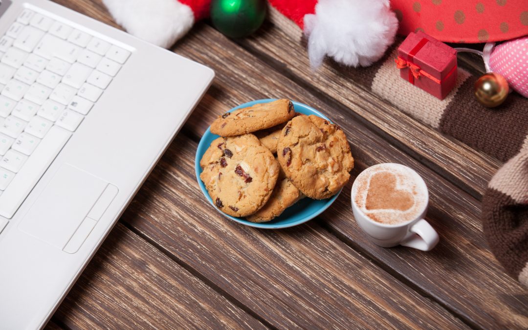 laptop and cookies with cup of coffee near Christmas gifts.