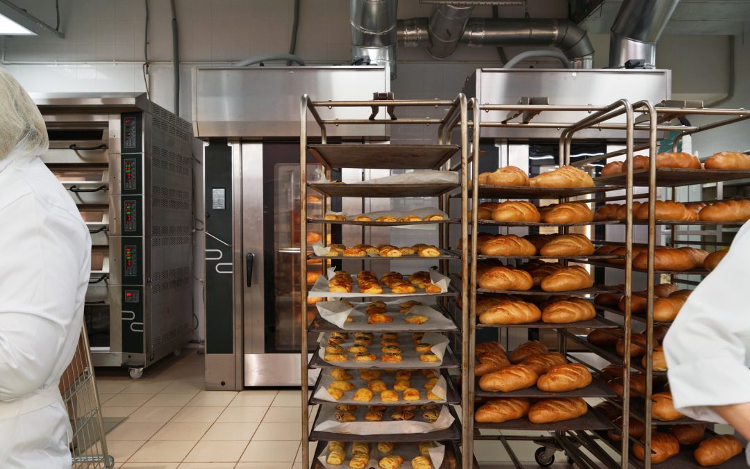 Racks of fresh loaves of bread and buns from ovens in Bakery